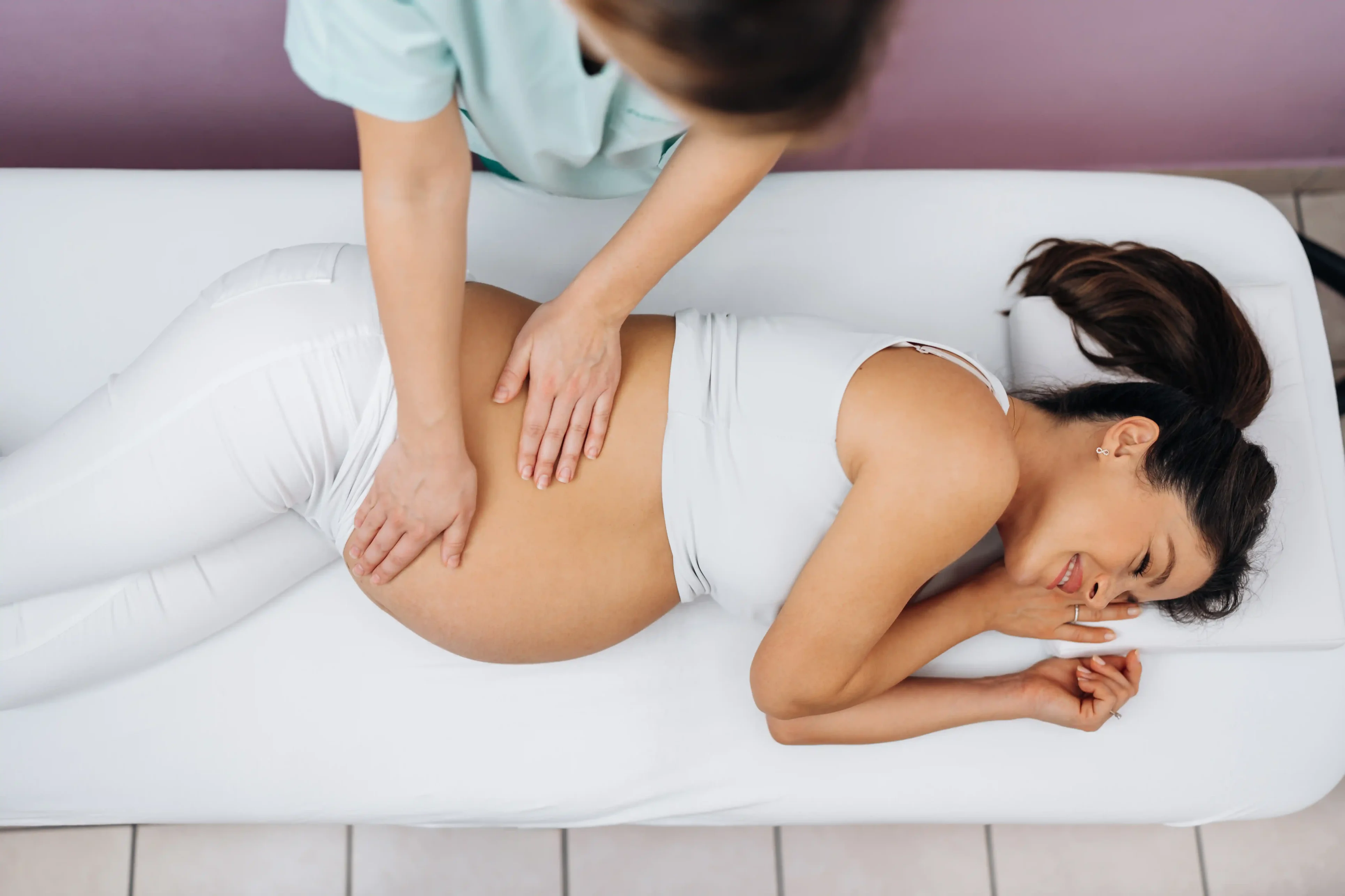 A woman is getting her belly button touched by a masseuse.